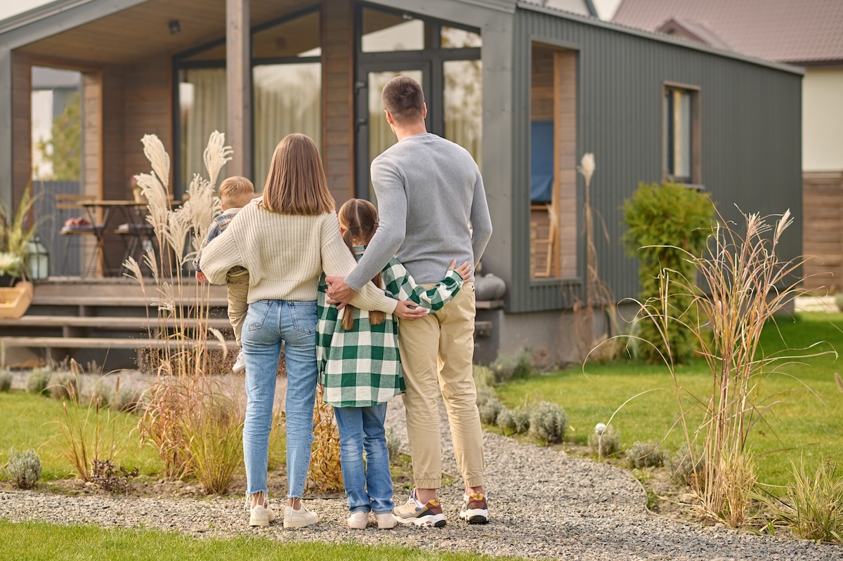 Back view of family hugging and admiring their home